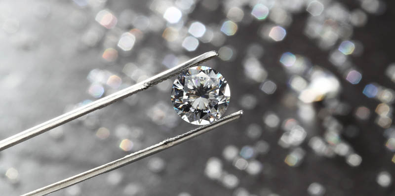 diamond held by tweezers close up.